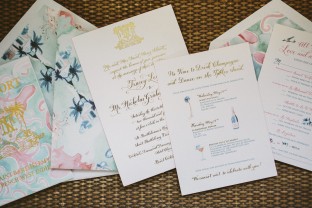 Gold foil stamped wedding invitations with tropical invitation sleeves and accessory pieces