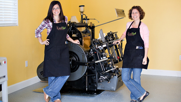 Gina and Katie Vallecorsa of LittleOwl Letterpress in front of their Heidelberg Windmill.